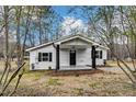 Charming home surrounded by trees and green grass with a covered front porch and a black door at 1323 Colon Rd, Sanford, NC 27330