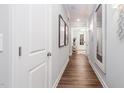 Bright hallway featuring wood floors, white trim, and decorative mirrors and artwork at 1502 Red Roses Ave, Durham, NC 27703