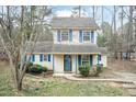 Inviting two-story home featuring blue shutters, a cozy porch, and a serene, wooded front yard at 3323 Nantuckett Ave, Durham, NC 27703