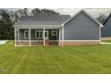 Backyard view of a house with gray siding and a covered porch, perfect for outdoor entertaining at 4037 Mebane Oaks Rd, Mebane, NC 27302