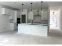 Open kitchen with white cabinetry, pendant lights, stainless appliances, and an eat-in island at 704 Compeer Way # 28, Rolesville, NC 27571