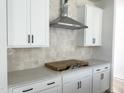 Bright kitchen featuring white cabinets, neutral backsplash, stainless hood vent, and light countertops at 704 Compeer Way # 28, Rolesville, NC 27571