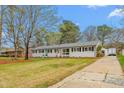 Charming single-story home with black shutters, a well-maintained lawn, a long driveway, and an inviting turquoise front door at 928 Hanford Rd, Graham, NC 27253
