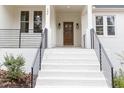 Inviting front porch featuring white brick stairs, black railings and a charming stained wood door at 100 High Ridge Ln, Pittsboro, NC 27312