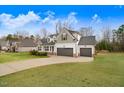 Beautiful view of home with a three car garage, green grass and inviting covered porch at 147 Everwood Dr, Four Oaks, NC 27524