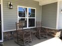 Inviting front porch with rocking chairs, creating a cozy outdoor space with stylish stone work at 149 Steep Rock Dr, Willow Springs, NC 27592