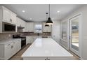Bright kitchen with white cabinets, stainless steel appliances, large island and pendant lighting at 2340 Beeblossom Pl, Fuquay Varina, NC 27526