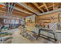 Unfinished basement with exposed beams, concrete floor, and work area at 309 College St, Oxford, NC 27565