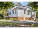 Side of home featuring a brick foundation, white siding, and access stairs at 309 College St, Oxford, NC 27565