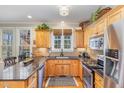 Cozy kitchen featuring warm wood cabinetry, granite countertops, stainless steel appliances, and natural light at 4704 Homeplace Dr, Apex, NC 27539