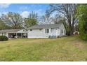 Quaint home with light gray siding, surrounded by lush trees and a spacious lawn, offering a serene residential setting at 513 Kenway St, Garner, NC 27529
