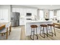 Modern kitchen with white cabinets, stainless steel appliances, quartz countertops and a large island with seating at 603 Silverado Sunset Loop, Wendell, NC 27591