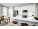 Modern kitchen with white cabinets, stainless steel appliances, quartz countertops and a large island with seating at 603 Silverado Sunset Loop, Wendell, NC 27591