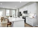 Modern kitchen with white cabinetry, stainless steel appliances, an island with seating, and a dining area at 609 Silverado Sunset Loop, Wendell, NC 27591