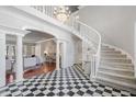 Grand foyer boasts black and white checkered floors, curved staircase and chandelier lighting at 100 Dunedin Ct, Cary, NC 27511