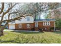Brick home with a manicured lawn and mature trees providing shade at 1004 Plateau Ln, Raleigh, NC 27615