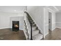 Elegant staircase with carpeted steps, a fireplace, and modern lighting, creating a welcoming ambiance at 1012 Mountain Laurel Dr, Raleigh, NC 27603