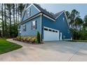 Side view of blue house with large garage, concrete driveway, and manicured landscaping at 110 Purslane Dr, Franklinton, NC 27525