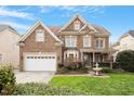 A beautiful two-story brick house featuring a manicured lawn and a lovely water fountain at 113 Kings Castle Dr, Apex, NC 27502