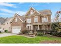 Stately brick home with manicured lawn, fountain, and two-car garage is situated beneath a partly cloudy sky at 113 Kings Castle Dr, Apex, NC 27502