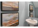 Stylish powder room with elegant pedestal sink, framed mirror, and artwork at 146 Holton St, Smithfield, NC 27577