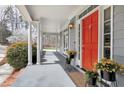 Inviting front porch with a vibrant red door, classic columns, and potted plants at 3424 Forest Oaks Dr, Chapel Hill, NC 27514
