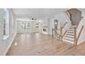 Bright living room featuring hardwood floors, fireplace, fan, and wooden staircase at 4706 Cypress Tree Ln, Raleigh, NC 27612