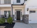Home's entryway with a dark-stained front door framed by sidelights, stone accents, and manicured landscaping at 518 Hampton Crest Ct, Fuquay Varina, NC 27526