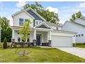 Charming two-story home with a two-car garage, landscaped yard, and blue accents at 789 Old Station Pointe, Angier, NC 27501