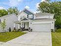 Charming two-story home with a two-car garage, landscaped yard, and blue accents at 789 Old Station Pointe, Angier, NC 27501
