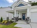 Inviting covered front porch with stone accents and a blue front door at 789 Old Station Pointe, Angier, NC 27501