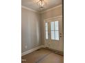 Entryway features a modern light fixture, neutral wall paint and a glass paneled white front door at 977 Lewis Rd, Zebulon, NC 27597