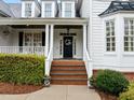 Inviting front porch with brick steps, white columns, and a decorative wreath on the black front door at 1188 The Preserve Trl, Chapel Hill, NC 27517