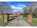 Long driveway with brick entrance pillars leading to a brick home, framed by mature trees and greenery at 1220 Bethlehem Rd, Knightdale, NC 27545