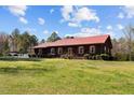 A beautiful single story house features a red metal roof, dark siding, and large grassy yard at 1796 Steel Bridge Rd, Sanford, NC 27330