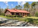 A lovely one-story home showcases red metal roof, dark siding, and well-maintained landscaping at 1796 Steel Bridge Rd, Sanford, NC 27330