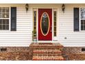 Inviting red front door with glass oval, flanked by side windows and black shutters, creating a warm welcome at 4324 Old Lewis Farm Rd, Raleigh, NC 27604