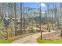 View of gray homes from the driveway, surrounded by a wooded area and white fences, showcasing the neighborhood setting at 4721 Cypress Ford Dr, Fuquay Varina, NC 27526