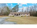 Ranch home with a large front yard, covered porch, and gravel driveway at 7155 Old Fairground Rd, Benson, NC 27504
