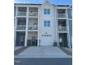 Back exterior of townhomes featuring white garages, doors, and balconies with railings at 829 S Franklin St, Wake Forest, NC 27587