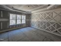 Unfinished bedroom with decorative wood accent wall and a large window overlooking a wooded view at 98 Fox Oak Trl, Pittsboro, NC 27312