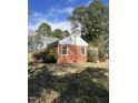 Brick exterior with greenery, showing a yard needing some maintenance and a home under a partly cloudy sky at 1101 W Divine St, Dunn, NC 28334