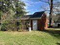 Brick shed with a white door, surrounded by greenery and a well-maintained lawn under a bright sky at 1101 W Divine St, Dunn, NC 28334