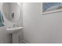 Clean half bathroom featuring a modern pedestal sink and round mirror at 1123 Latitude Dr, Durham, NC 27713