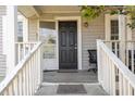 Inviting front porch featuring a black door, open sidelight, and weathered white railings at 1614 Homewood Ave, Durham, NC 27707