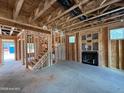 Unfinished living room featuring a fireplace, a staircase, exposed framing, and rough concrete flooring at 200 Dove Rd, Cameron, NC 28326