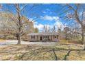Exterior view of the home with gravel driveway and mature trees on a sunny day with blue skies at 2914 Old Stage N Rd, Coats, NC 27521