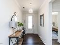 Bright entryway featuring a modern light fixture, wood floors, and views into the office space at 521 Ivy Arbor Way, Holly Springs, NC 27540