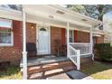 Inviting covered front porch with seating, red shutters and brick facade at 5630 Jones Sausage Rd, Garner, NC 27529