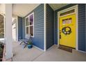 Close-up of a vibrant yellow front door with decorative wreath and cozy seating area at 923 Sagamore Dr, Louisburg, NC 27549